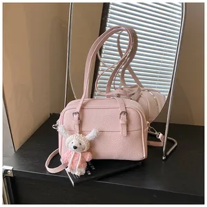 Pink lychee leather crossbody bag with a cute white crochet rabbit charm detail