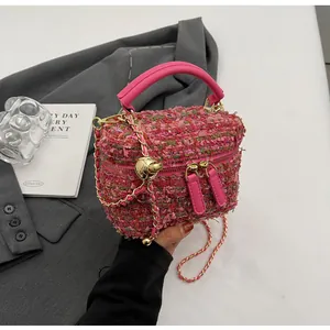 Detail der rosa Tweed-Eimertasche mit goldenem Kettenriemen und Metallkugel-Anhänger