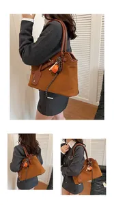 Close-up of brown suede tote bag with leather strap and decorative strawberry charm