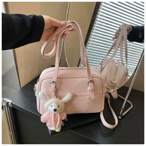 Detail of pink lychee grain leather handbag with silver zipper and cute plush bunny charm