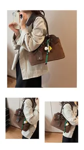 Detail of vintage brown suede tote bag with woven green rope and baseball charm