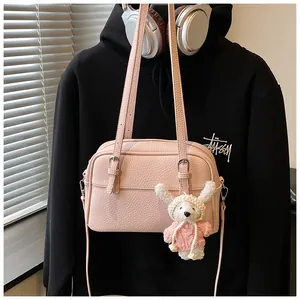 Pink lychee texture crossbody bag with cute bunny charm on a casual black sweatshirt