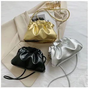 Macro shot of stylish ruched mini cloud bags in metallic gold, silver and black colors
