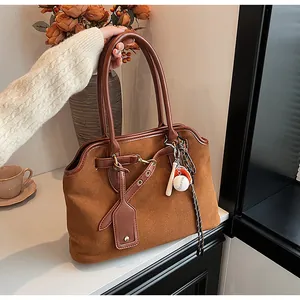 Detail of retro suede shoulder bag featuring baseball charms and leather strap accents