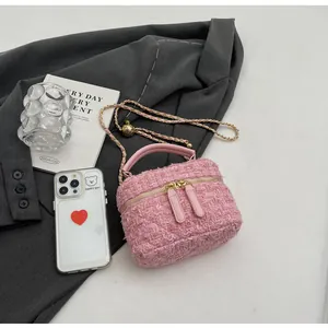 Detailaufnahme einer rosa Tweed-Kosmetiktasche mit Ledergriff und goldener Kette
