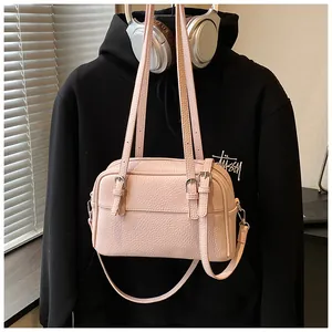 Detailed macro view of the pink litchi grain texture and metal buckle on crossbody bag
