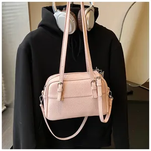 Close-up of pink lychee pattern crossbody bag with metal buckles and stylish headphones