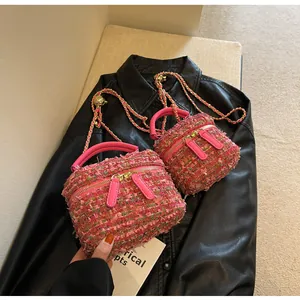 Nahaufnahme der rosa Tweed-Kosmetiktaschen mit Ledergriffen und Goldkettenriemen