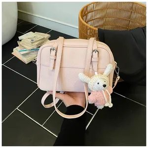 Detail of pink lychee texture shoulder bag with cute white rabbit plush keychain charm