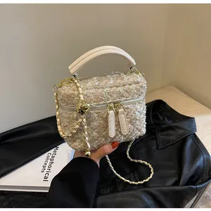 Detail der eleganten Tweed-Textur mit goldenem Herz-Metallanhänger an der Handtasche