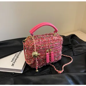 Detailaufnahme der rosa Tweed-Beuteltasche mit Kettenriemen und goldenem Anhänger