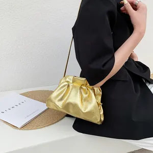Metallic gold pleated cloud bag with thin gold chain strap shown on a black outfit