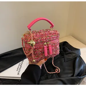 Detailaufnahme der rosa Tweed-Textur mit goldener Kette auf einer Designer-Tasche
