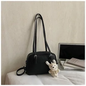 Close-up of black lychee grain leather crossbody bag with rabbit charm and silver buckle