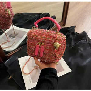 Detail der rosa Tweed-Handtasche mit gewebter Textur, Doppelreißverschluss und Goldanhänger