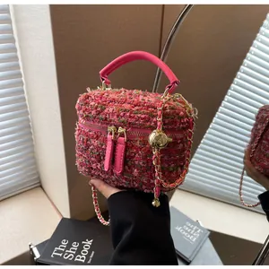 Detail der pinkfarbenen Tweed-Handtasche mit goldener Kette und dekorativer Metallkugel