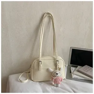 Detail of off-white lychee texture bag with silver metal buckles and plush rabbit charm