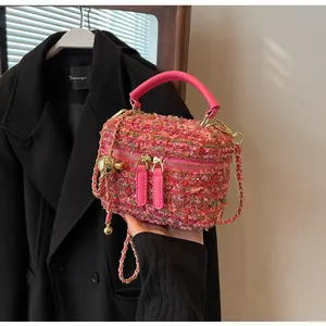 Detail der rosa Tweed-Handtasche mit goldener Kette und metallischen Akzenten