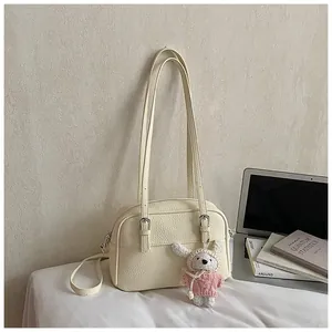 Detail of off-white lychee grain leather crossbody bag with cute rabbit pendant