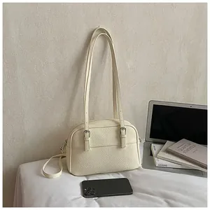 Detail of cream lychee texture leather shoulder bag with silver metal buckles and straps