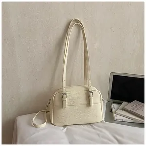 Detail of lychee textured cream crossbody bag with silver buckles and dual shoulder straps