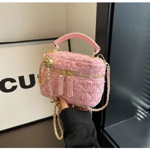 Detail der rosa Tweed-Beuteltasche mit gewebter Textur, Metallkugel-Anhänger und Goldkette