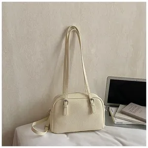 Close-up of cream lychee texture leather shoulder bag with fine stitching and buckles