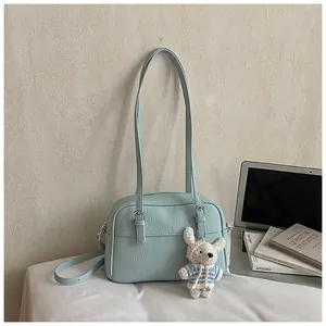 Detail of light blue lychee pattern leather bag with a cute white rabbit plush charm