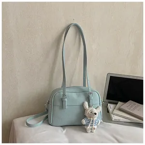 Detail view of light blue lychee pattern bag with dual handles and cute rabbit charm