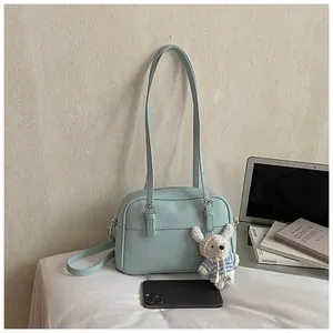 Detail of light blue lychee pattern crossbody bag with cute teddy bear charm accessory