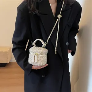 Mini-Handtasche aus Tweed in Cremeweiß mit goldener Kette auf schwarzem Blazer