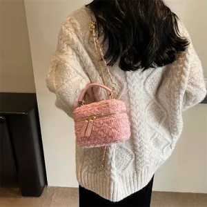 Rosa Tweed-Umhängetasche mit Kettenriemen am Modell im weißen Strickpullover
