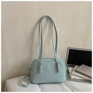 Detail of light blue lychee pattern faux leather handbag with adjustable straps and silver hardware