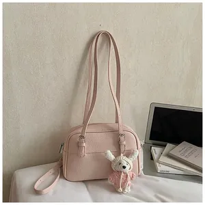 Detail of pink lychee texture leather shoulder bag with a cute crochet doll charm