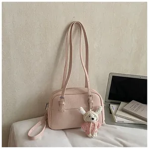Pink lychee texture shoulder bag with cute white knitted bear charm in lifestyle setting