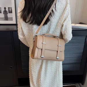 Detail view of apricot crossbody bag with pebble texture and decorative buckles on a model
