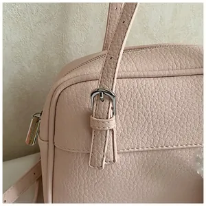 Close-up of pink lychee leather texture with silver buckle and zipper detailing