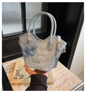 Vue détaillée du sac seau tissé bleu ciel avec breloque chien sur socle en marbre