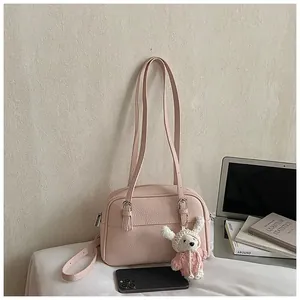 Detailed view of pink lychee texture shoulder bag with a cute white knit bear pendant
