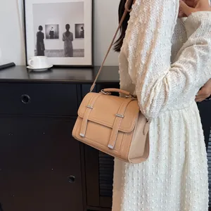 Chic beige crossbody bag with top handle and vintage straps shown on a model