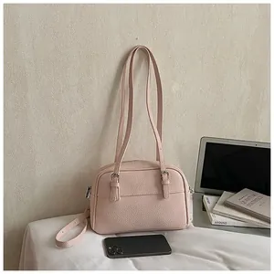 Detailed view of pink lychee leather handbag with silver buckles and zipper on a desk