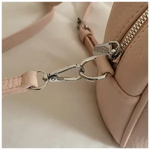 Detailed macro view of silver lobster clasp and D-ring on pink pebble leather handbag