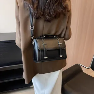 Detail of black textured leather crossbody bag with silver hardware and top handle strap