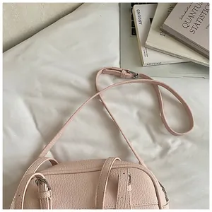 Detail of light pink lychee pattern leather bag with adjustable strap and silver buckle