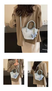 Détail du sac seau tissé bleu clair avec poignées en cuir et porte-clé ours mignon