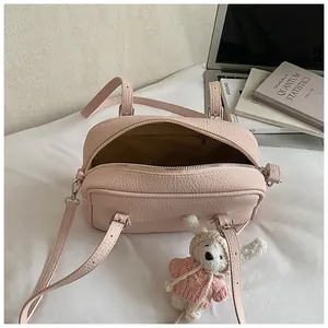 Detail of light pink lychee texture shoulder bag with cute white knit rabbit charm