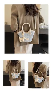 Détail du sac seau tissé bleu clair avec poignées en cuir crème et breloque petit chien