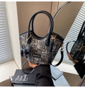 Détail du sac seau avec motif pixel, garniture en cuir et breloque éléphant chic