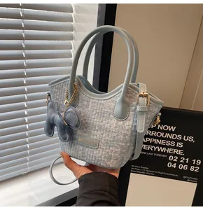 Gros plan sur sac seau bleu clair à texture tressée avec breloque éléphant en cuir