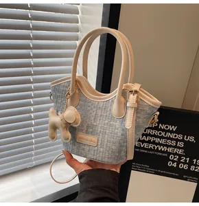 Détail du sac seau en tweed avec garniture en cuir beige et breloque en forme de chien